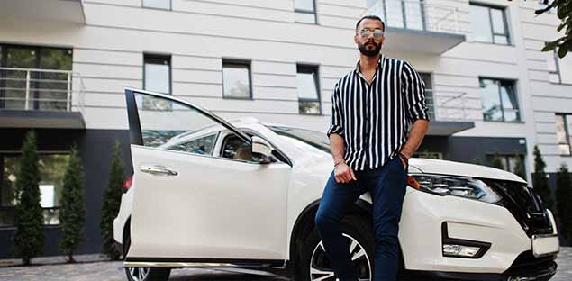 Man in striped shirt leaning against a white SUV  - keatsagency.com