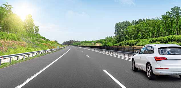 White SUV driving on a sunlit highway - keatsagency.com