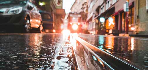 Wet city street at low angle with tram tracks reflecting light - keatsagency.com