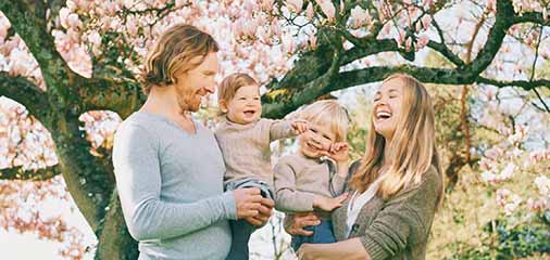 Family of four standing under blooming cherry trees - keatsagency.com