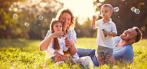 Family sitting on grass at golden-hour park -  https://keatsagency.com/