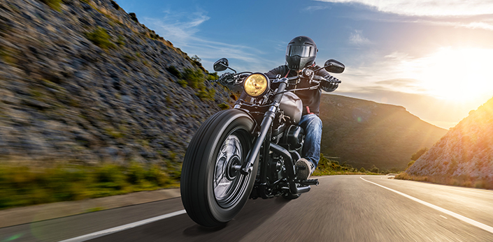 Custom cruiser motorcycle ridden on winding mountain road at sunset - keatsagency.com