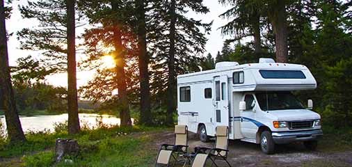Motorhome parked in forest by lake at sunset - keatsagency.com